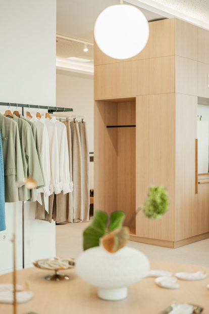 Foto, das das elegante und minimalistische Interieur des Ukiyo Wien Ladens zeigt, mit Holzakzenten und Auslagen von Kleidungsstücken, die zum Kauf angeboten werden.